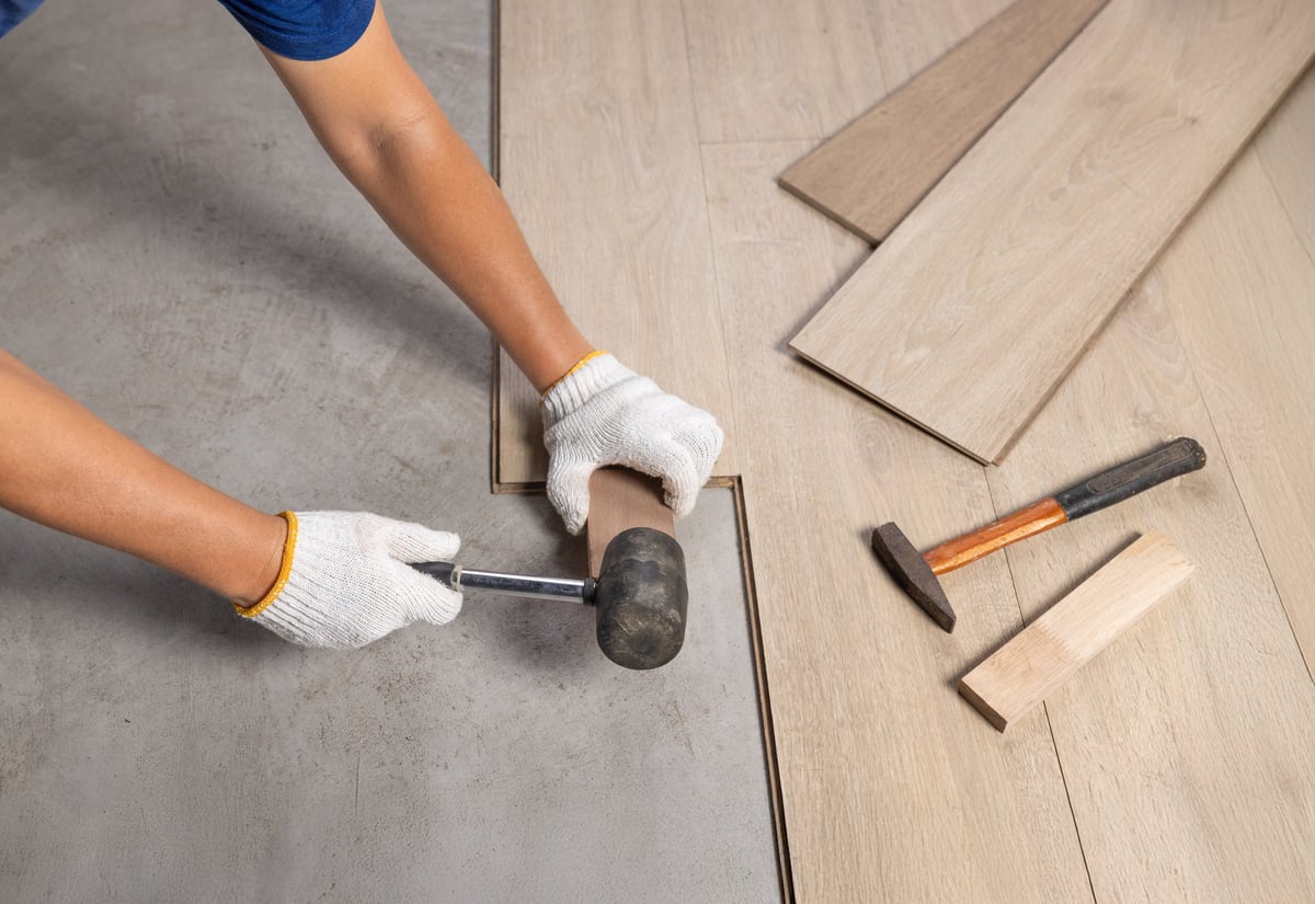 Worker Installing Interlocking laminate floor, home renovation.