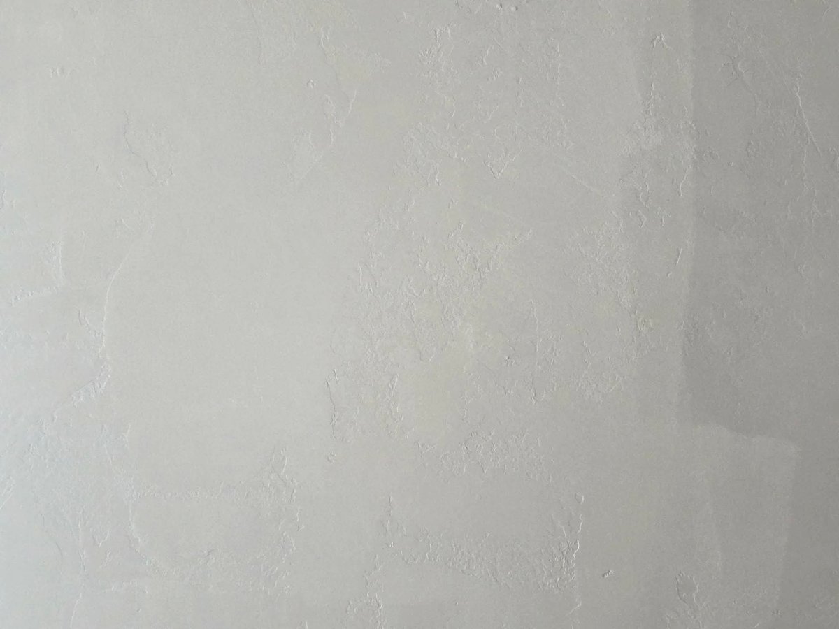 Close-up of white textured plaster or drywall surface with slight variations in shading