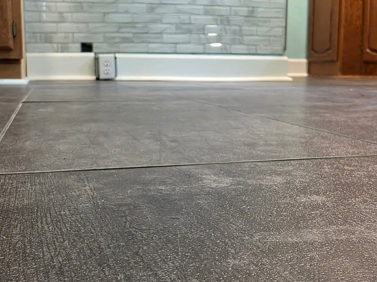 Modern bathroom with gray tile flooring, white vanity counter, subway tile backsplash, and wooden cabinet doors