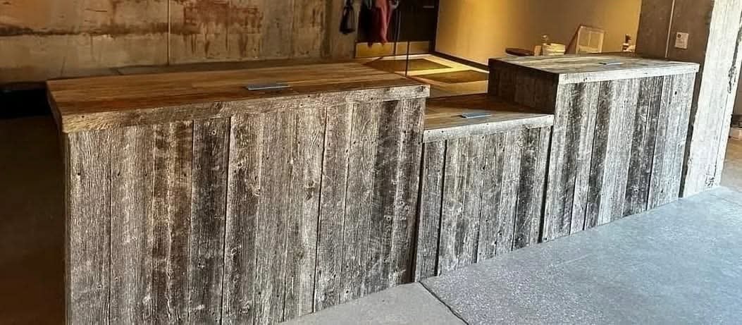 Modern reception desk with weathered wood grain paneling featuring curved white and gray striped sections in a contemporary office lobby
