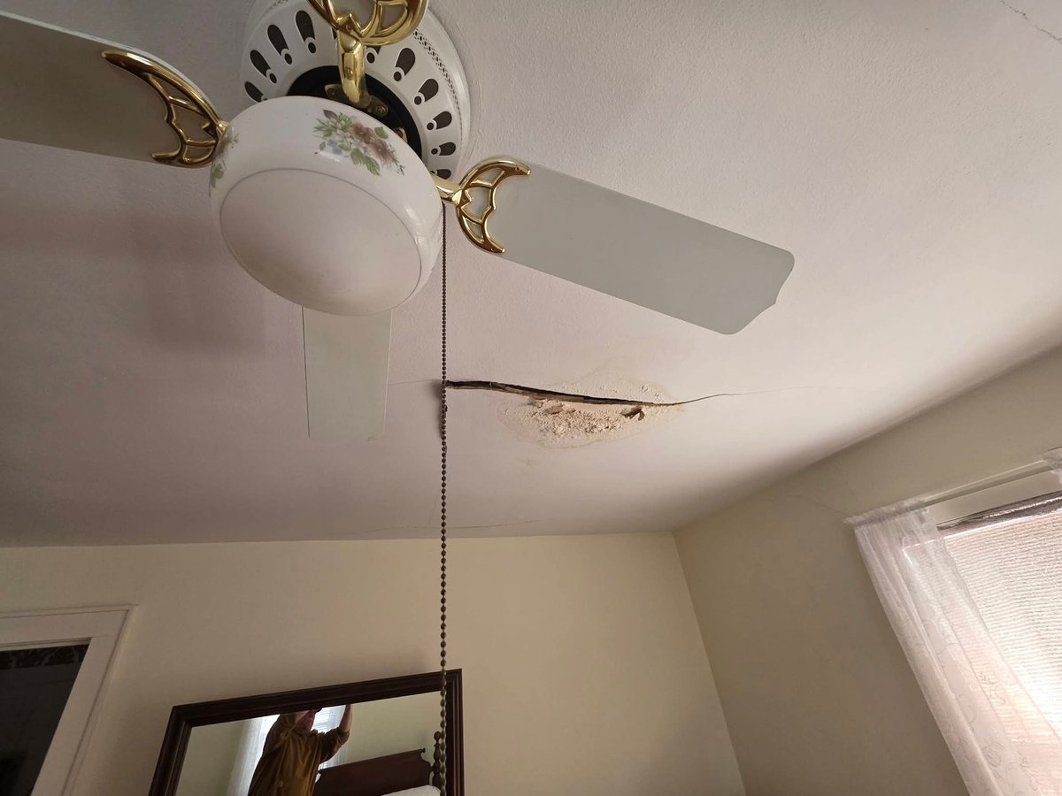 Ceiling fan with white bowl light fixture and brass accents mounted on beige ceiling in home interior