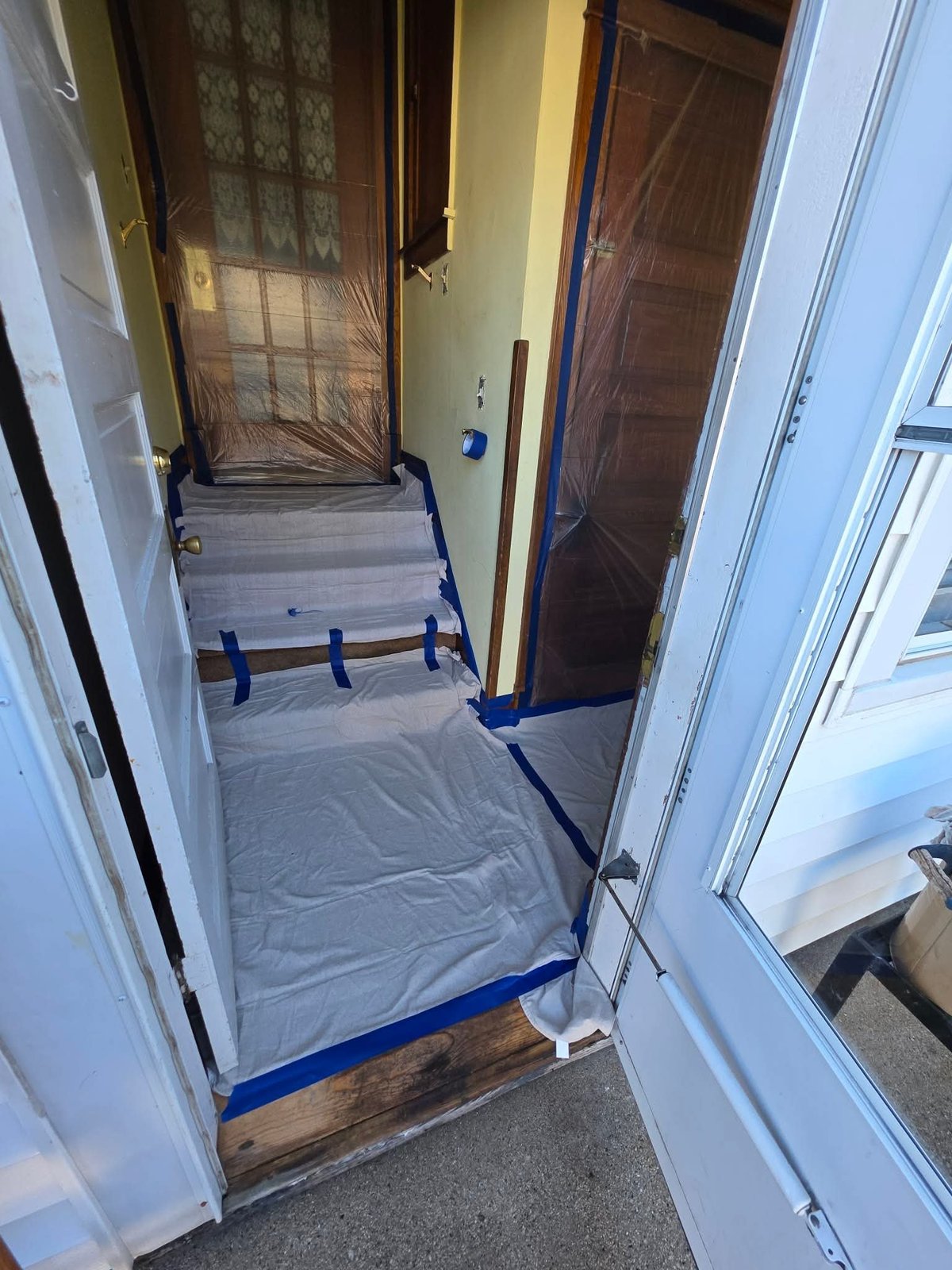 Narrow hallway with plastic sheeting and blue tape blocking off an area during home renovation or construction work