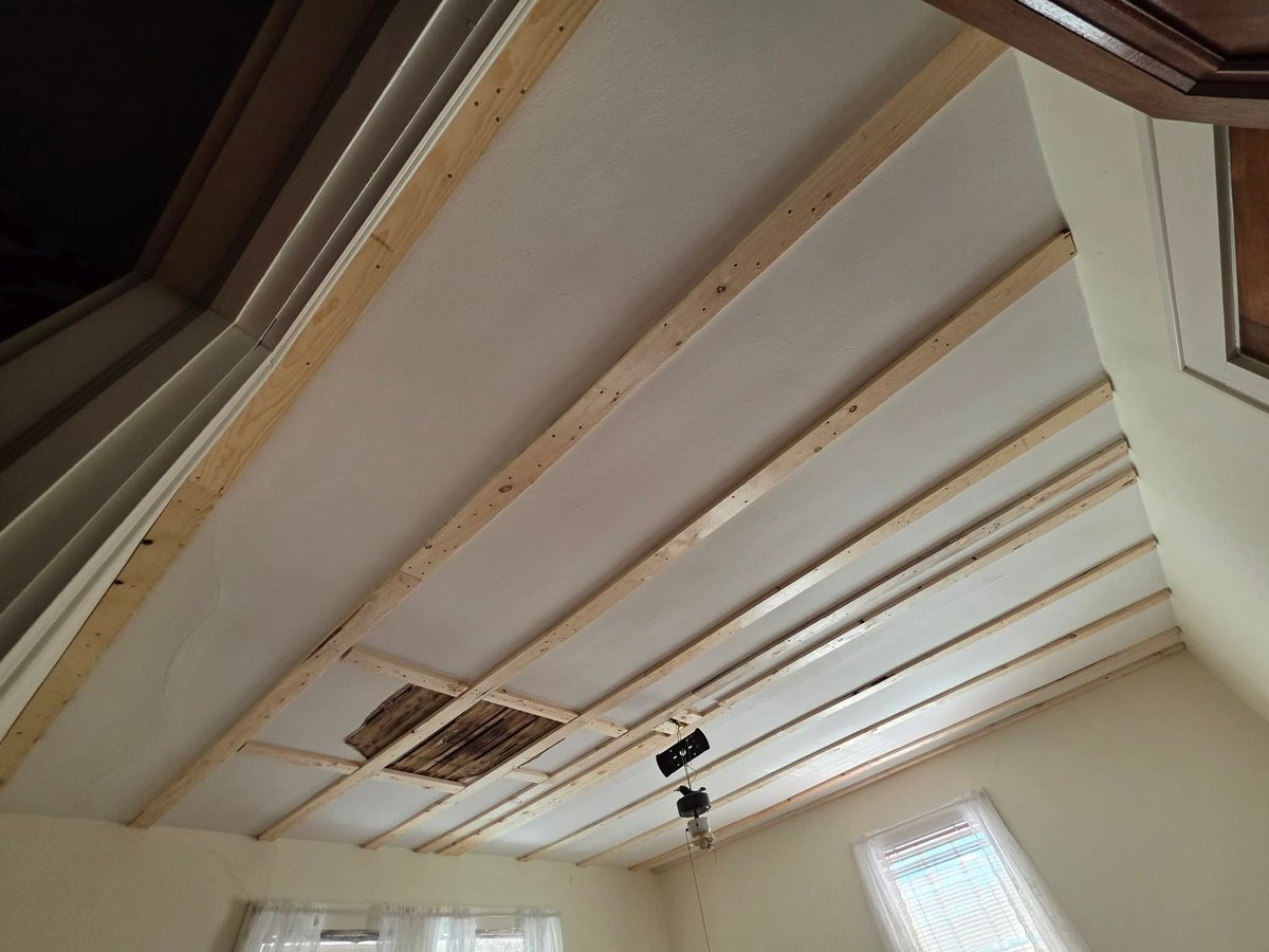 Interior ceiling with exposed wooden beams and recessed lighting fixtures under construction or renovation